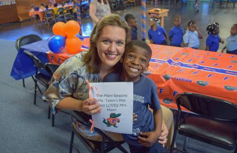 Lauren May in classroom with student, smiling for camera.