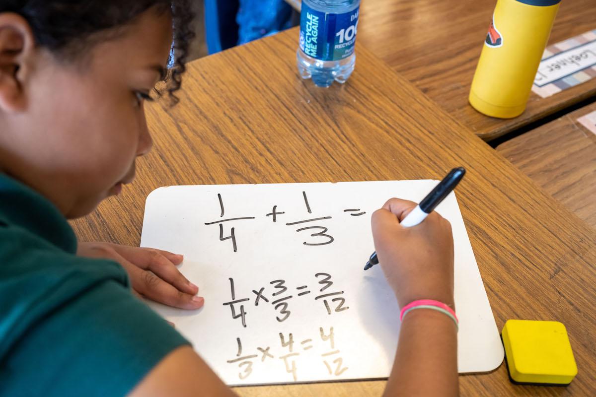 Student working on math problems on a white board