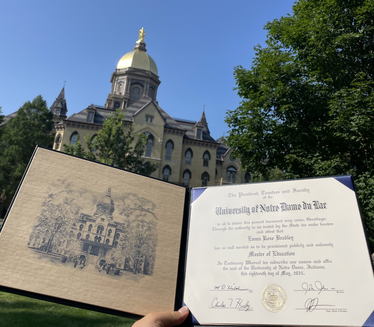 Emma Bradley's diploma in front of the Golden Dome