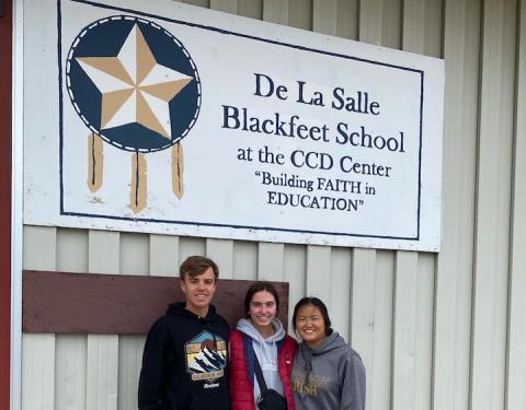 Jeremy, Katie, and Rose in from on De La Salle Blackfeet School's sign