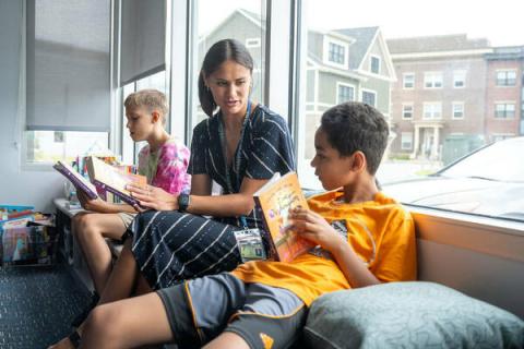 ACE teacher Rachel Erhart sits on a window bench reading alongside Braxton, 11, and Daniel, 11, left to right. The boys participated in the Summer Scholars program at RCLC.