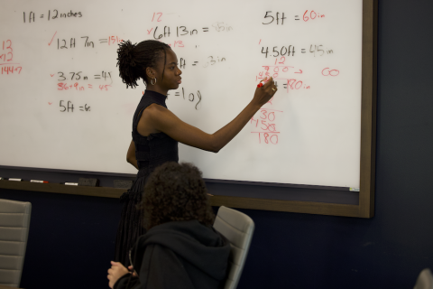 ACE Teacher Stephanie Ona writing math problems on the board