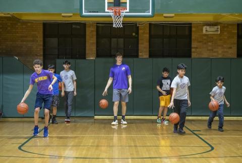 ACE Teacher Joey Jegier dribbling the basketball and coaching his students at his school gym