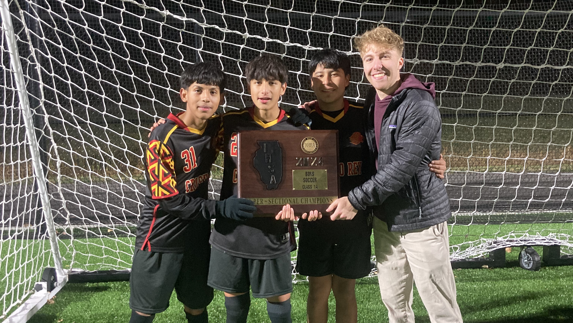 Mike Hanisch (Right) holding a section soccer trophy with his three students to his left